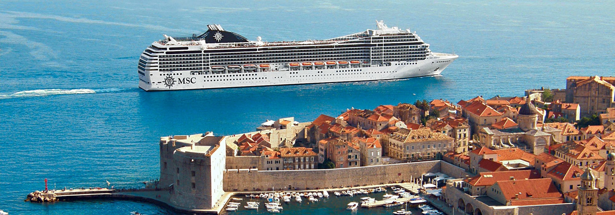 Ett MSC fartyg utanför en vacker kust med byggnader i Medelhavet.