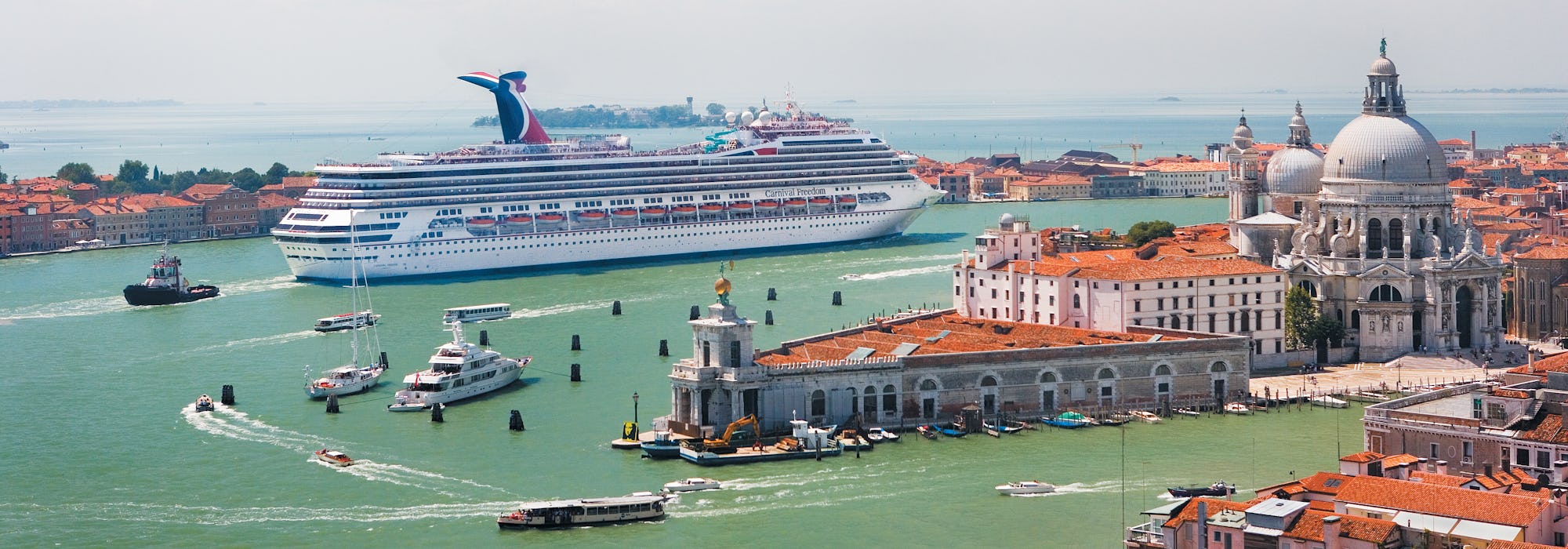 Carnival Freedom kryssar fram mellan färgglada byggnader i Medelhavet.