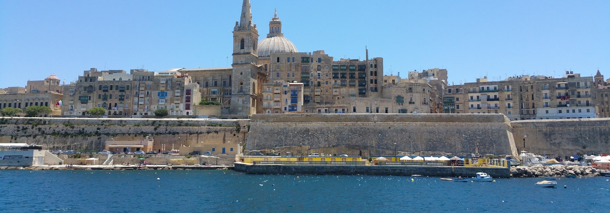 Bild på havet och Vallettas byggnader och stenmur.