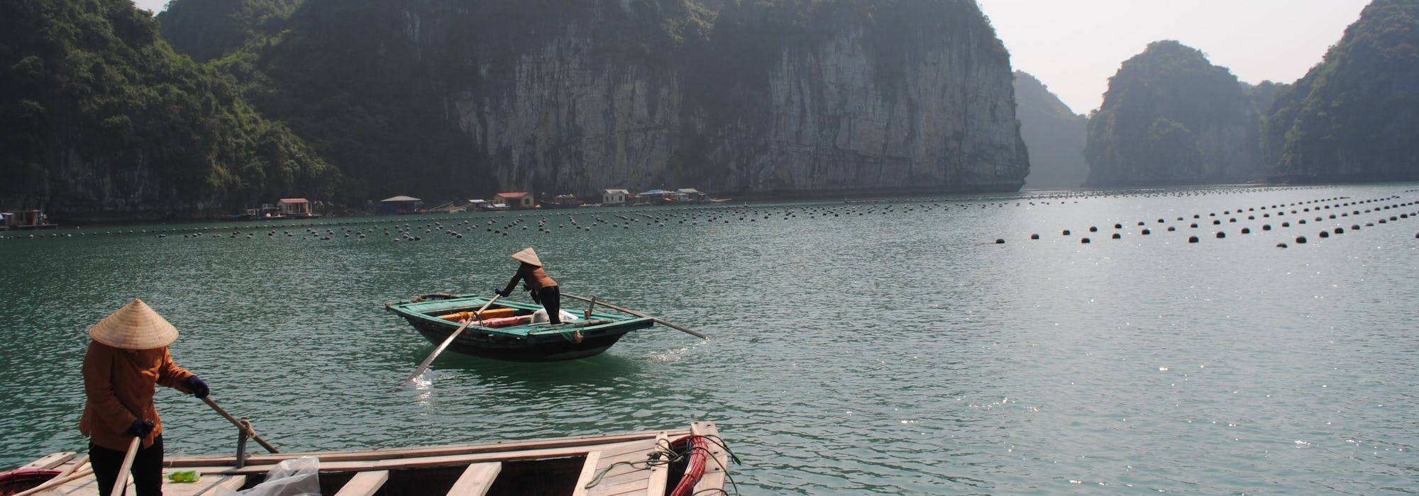 Två människor i båtar paddlar fram framför vackra berg.