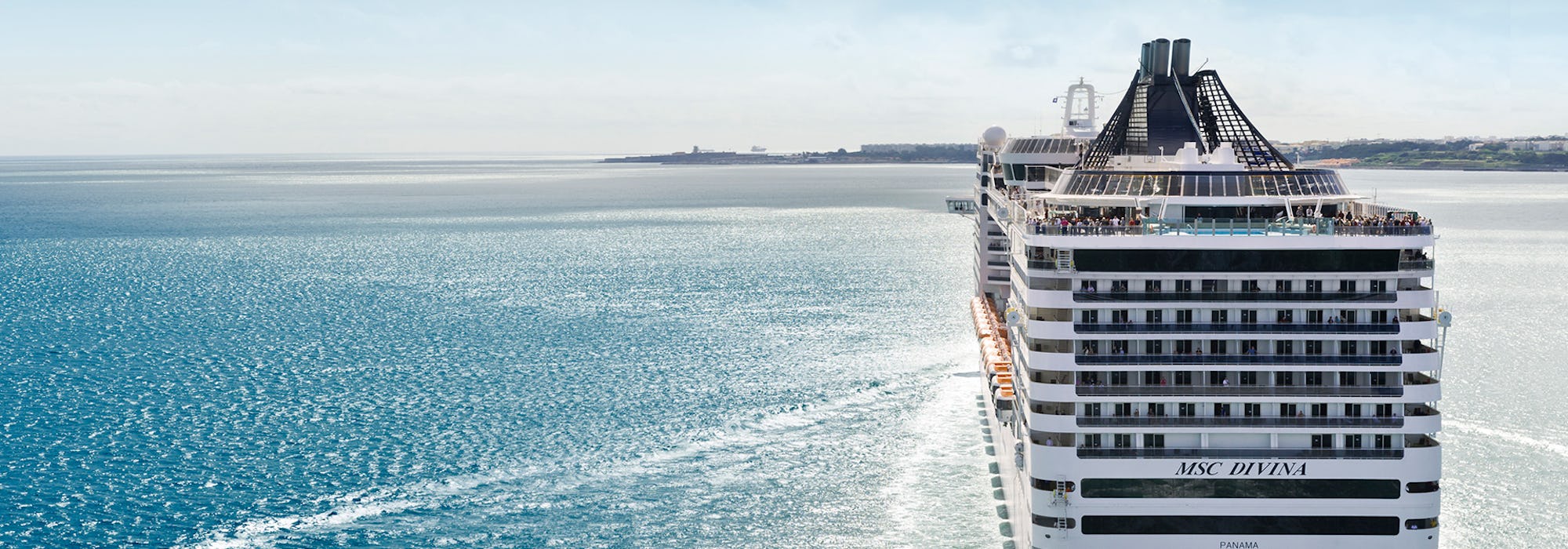 Bild på aktern på MSC Divina som närmar sig en hamn.