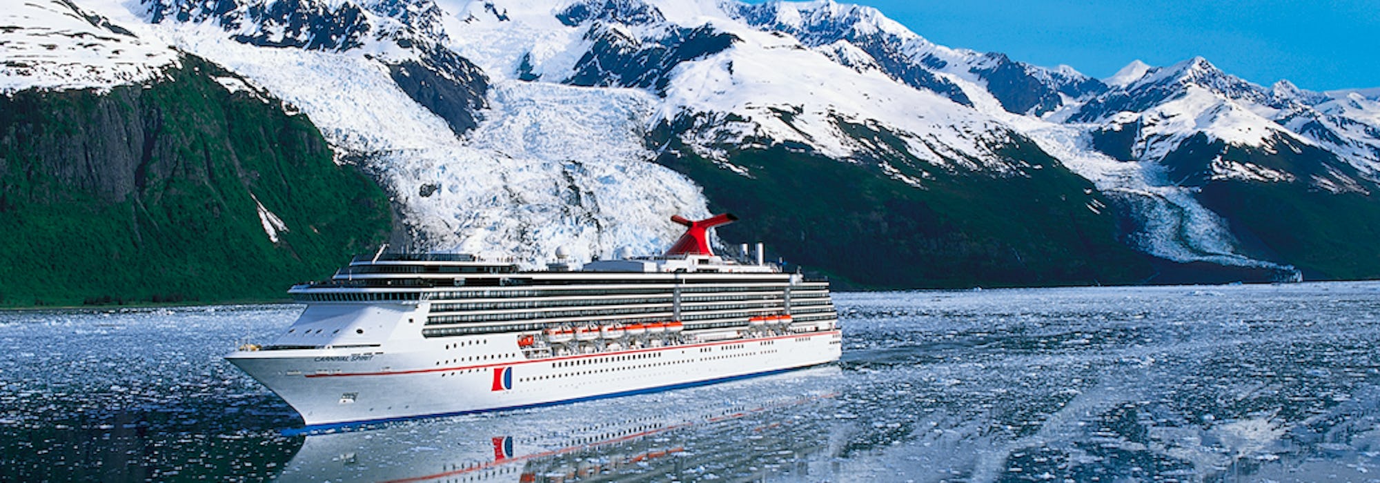 Carnival Spirit kryssar fram i Alaska med snötäckta berg i bakgrunden.