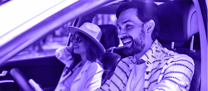 Pareja sonriente conduciendo un coche