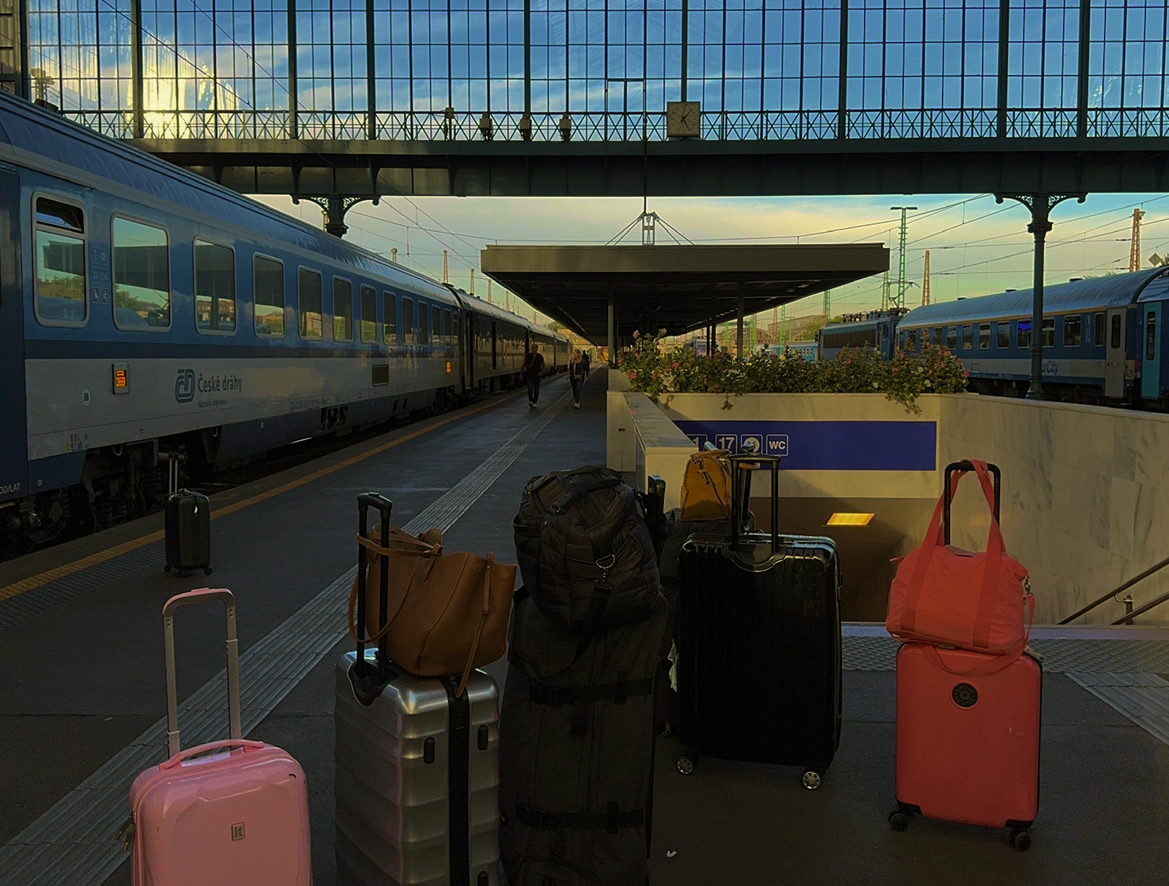 Equipaje esperando en una estación de tren con dos trenes en el andén.