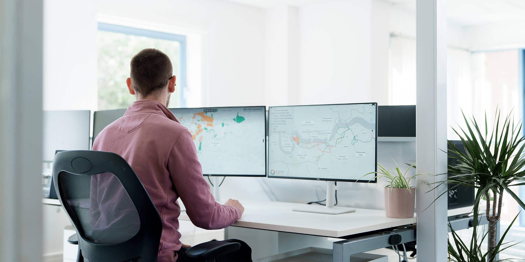 Man sat at desk looking at plans on monitors