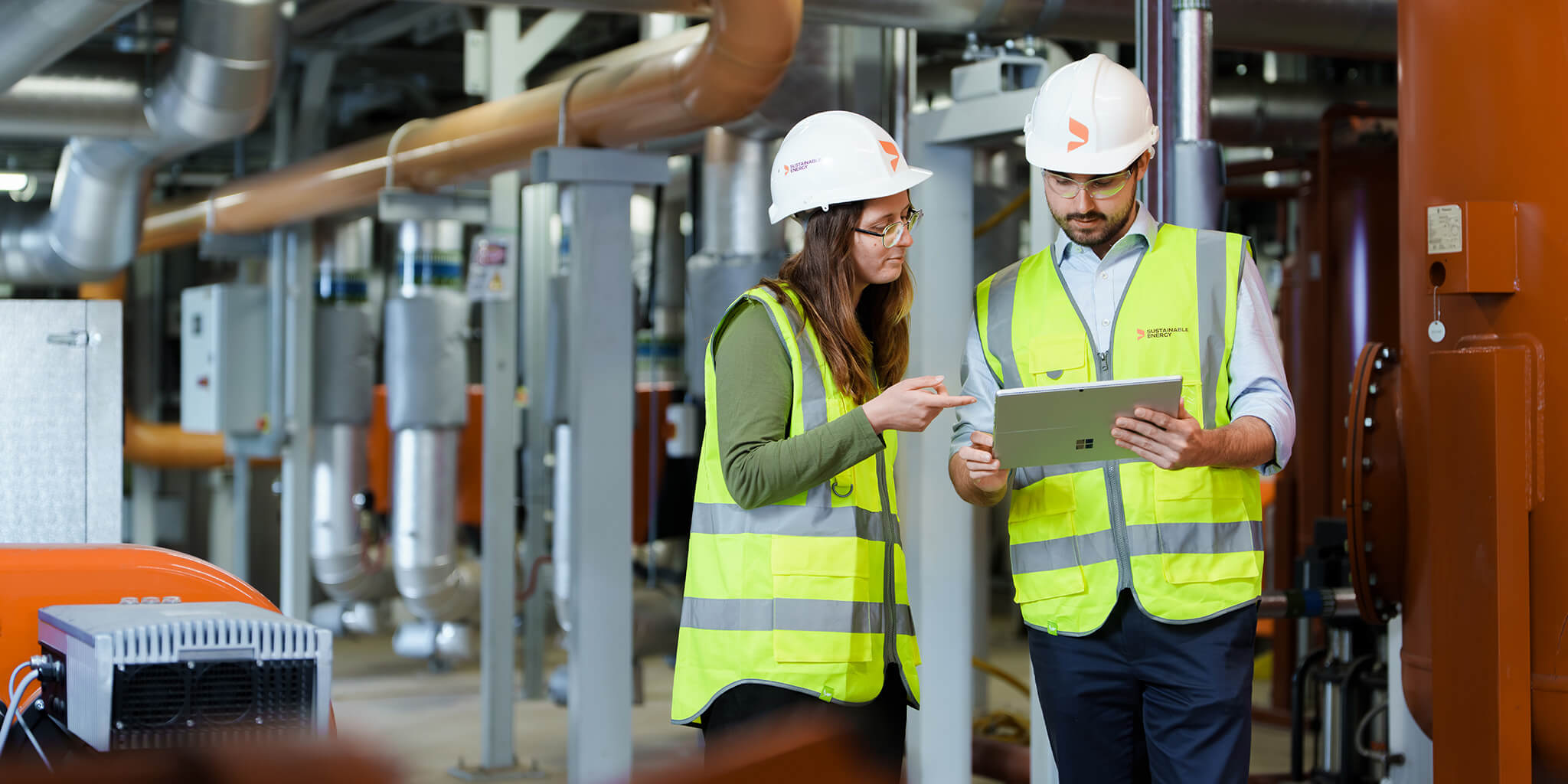 Two engineers on-site reading an energy report