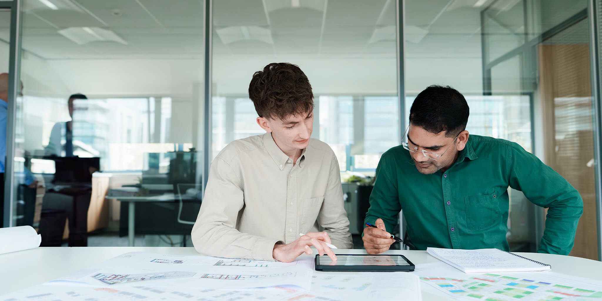 Two colleagues in an office looking at plans