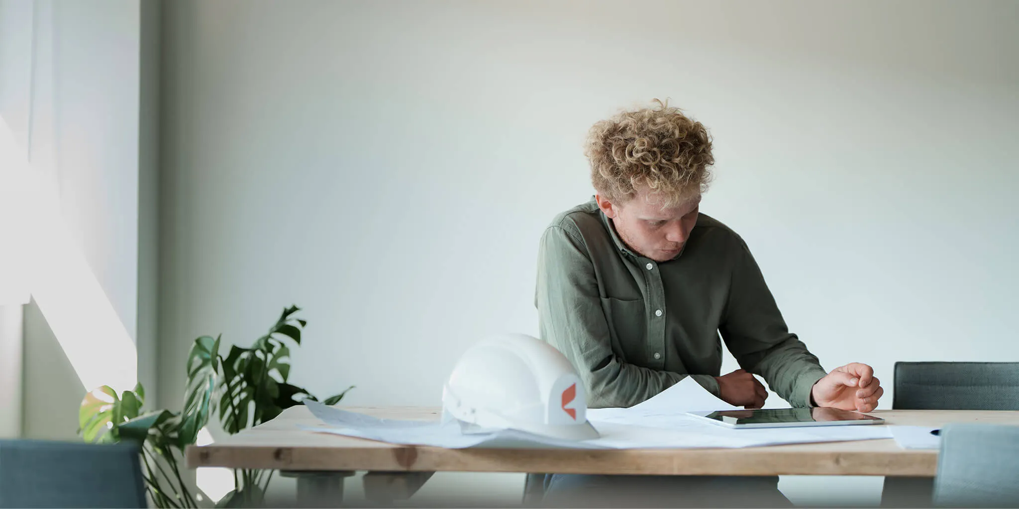 Employee sitting at a desk examining plans on a tablet
