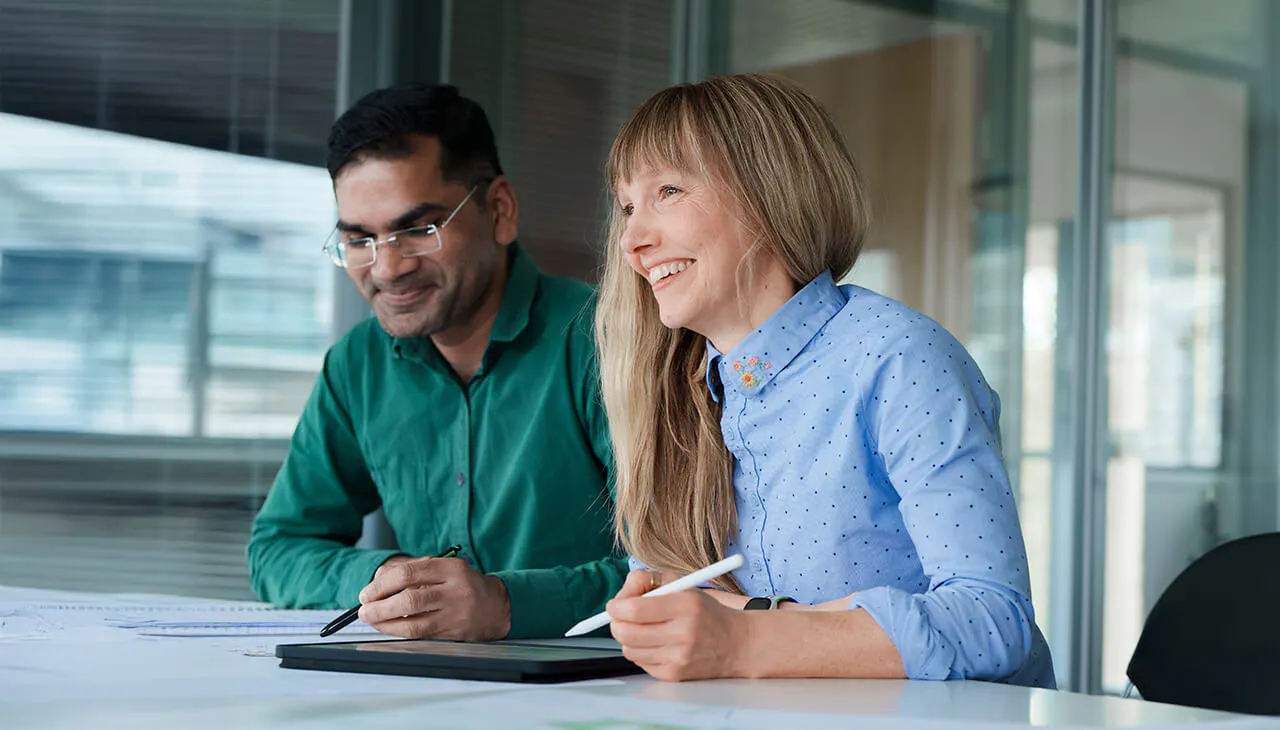 Two employees sat at a desk working on an iPad