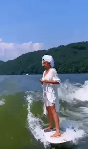 A woman drinking her coffee on a surfboard