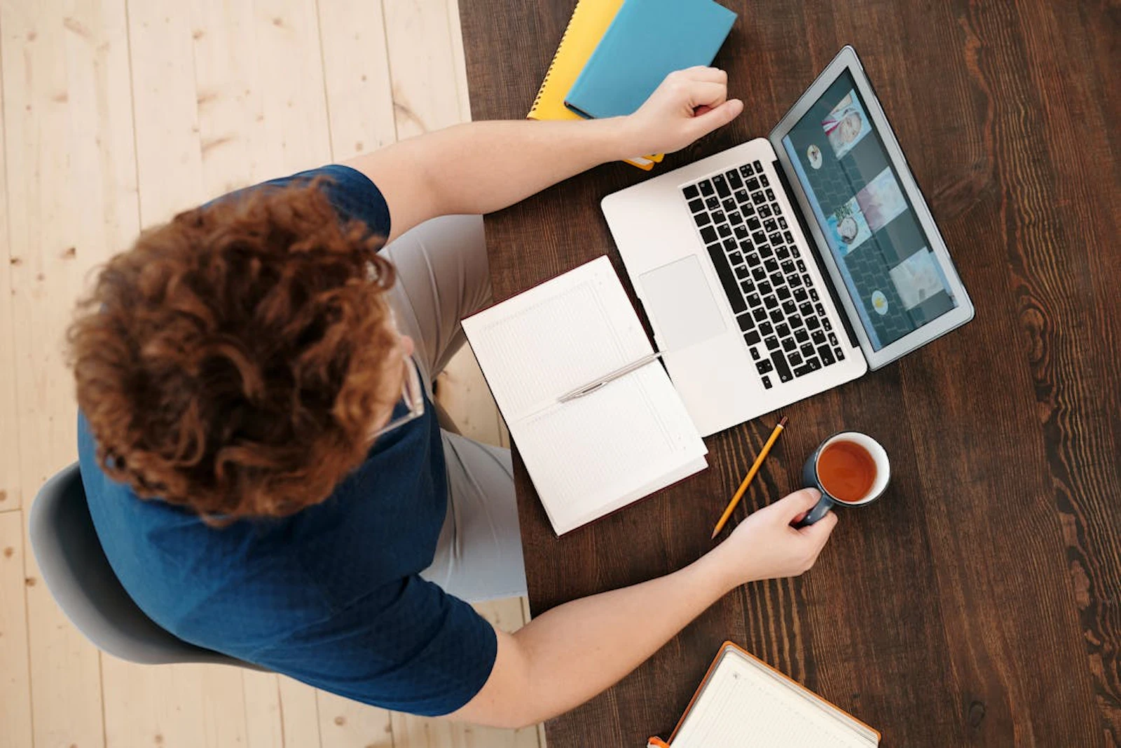 aerial view of an employee working on their laptop holding a coffee mug