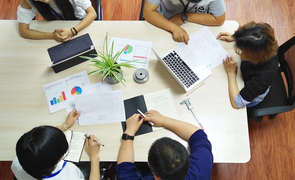 Overhead view of diverse team collaborating around a table with charts, laptop, and documents