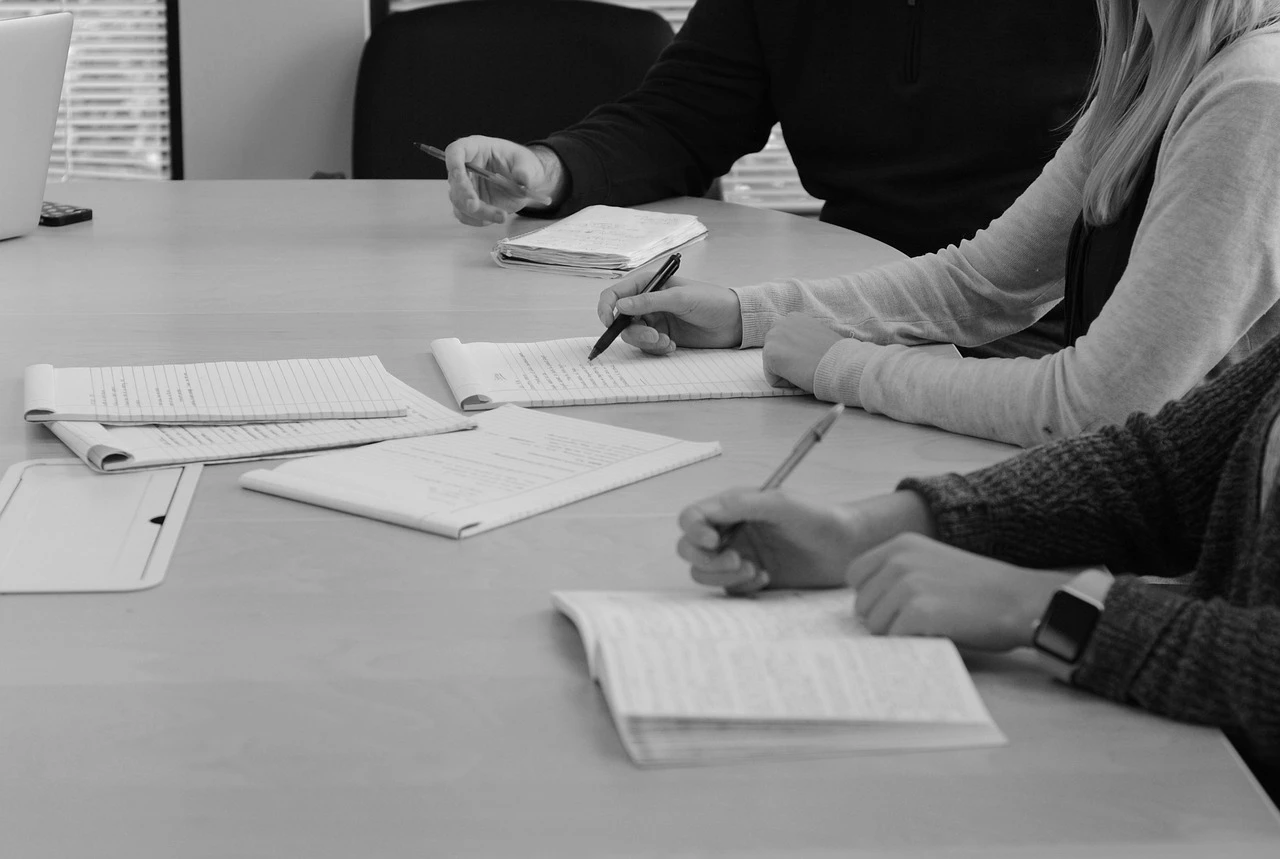 Two colleagues taking notes at a desk during a work session