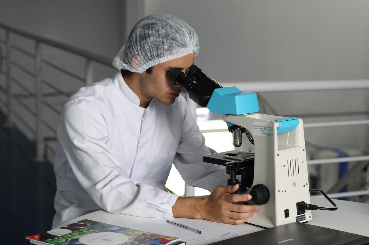 a pharmaceutical scientist looking into a microscope