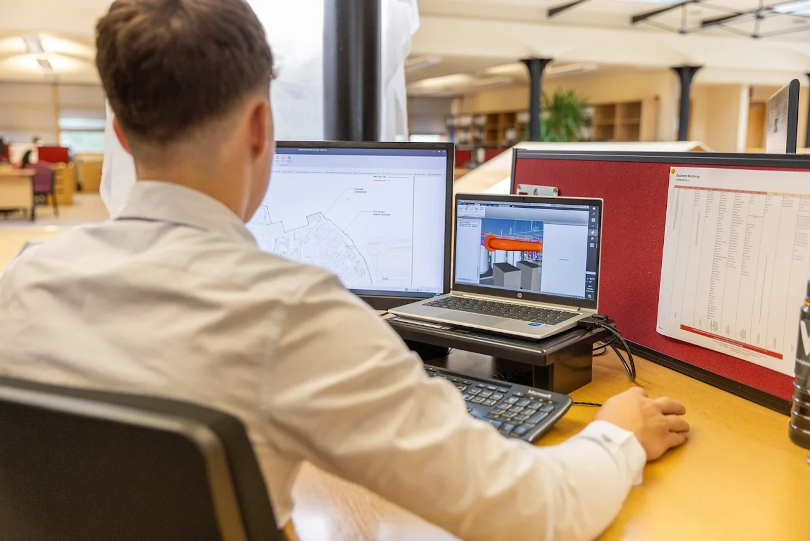 Man working at a desktop computer with dual screens in a corporate office environment