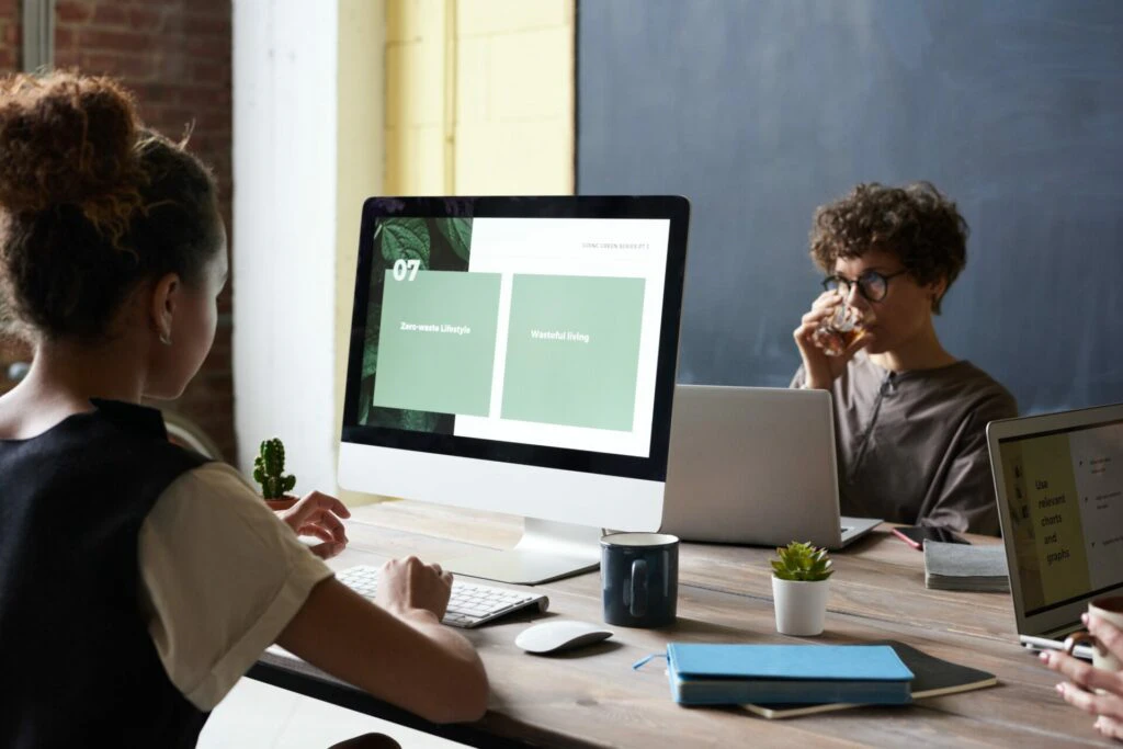 two people working at desks with monitors in a modern office
