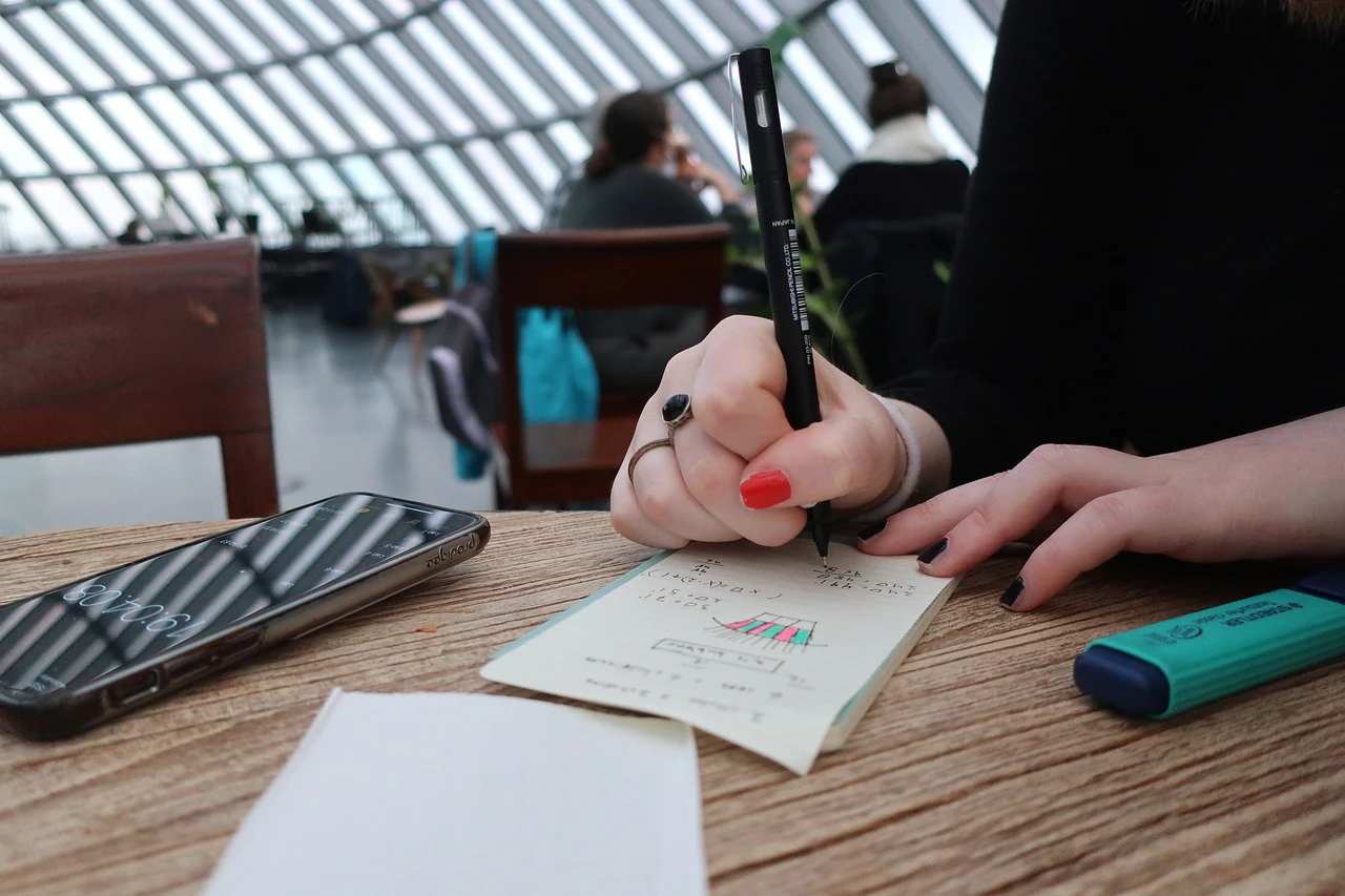 woman doing a calculation on a piece of paper in a cafe
