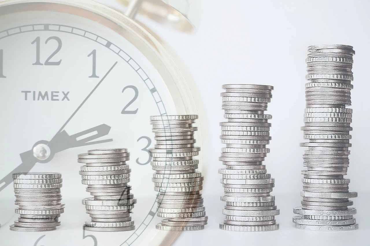 a row of stacked coins and a clock in the back