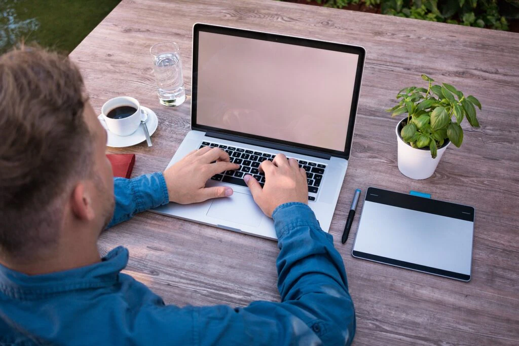 A remote employee working on his laptop on a desk in the outdoors