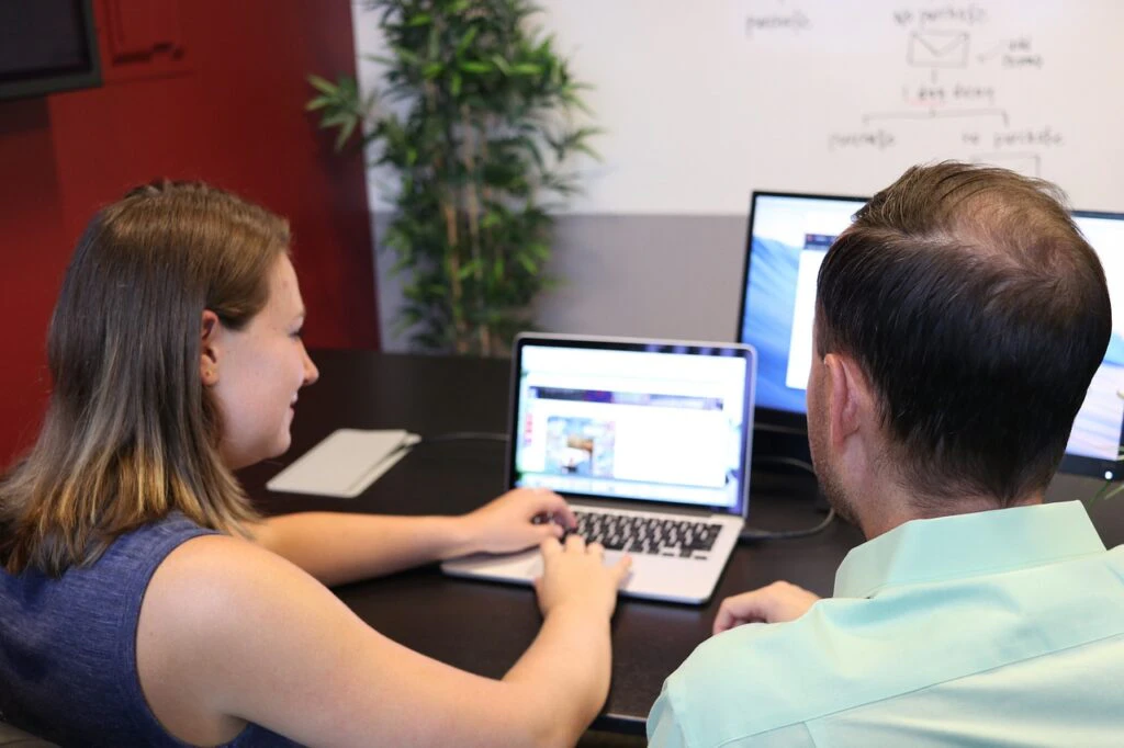 Two colleagues collaborating on a laptop at an office desk