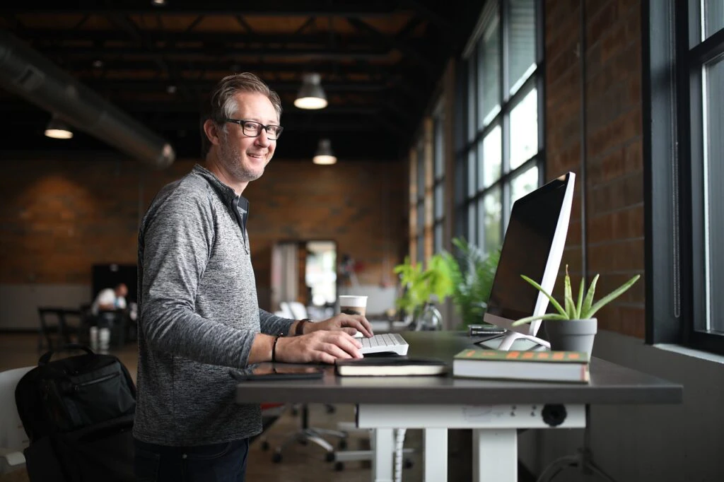 Smiling man working at a standing desk in a modern industrial-style office