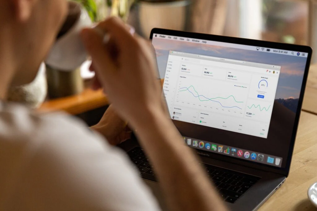 Person viewed from behind working on a MacBook laptop in a warm, dimly lit home setting