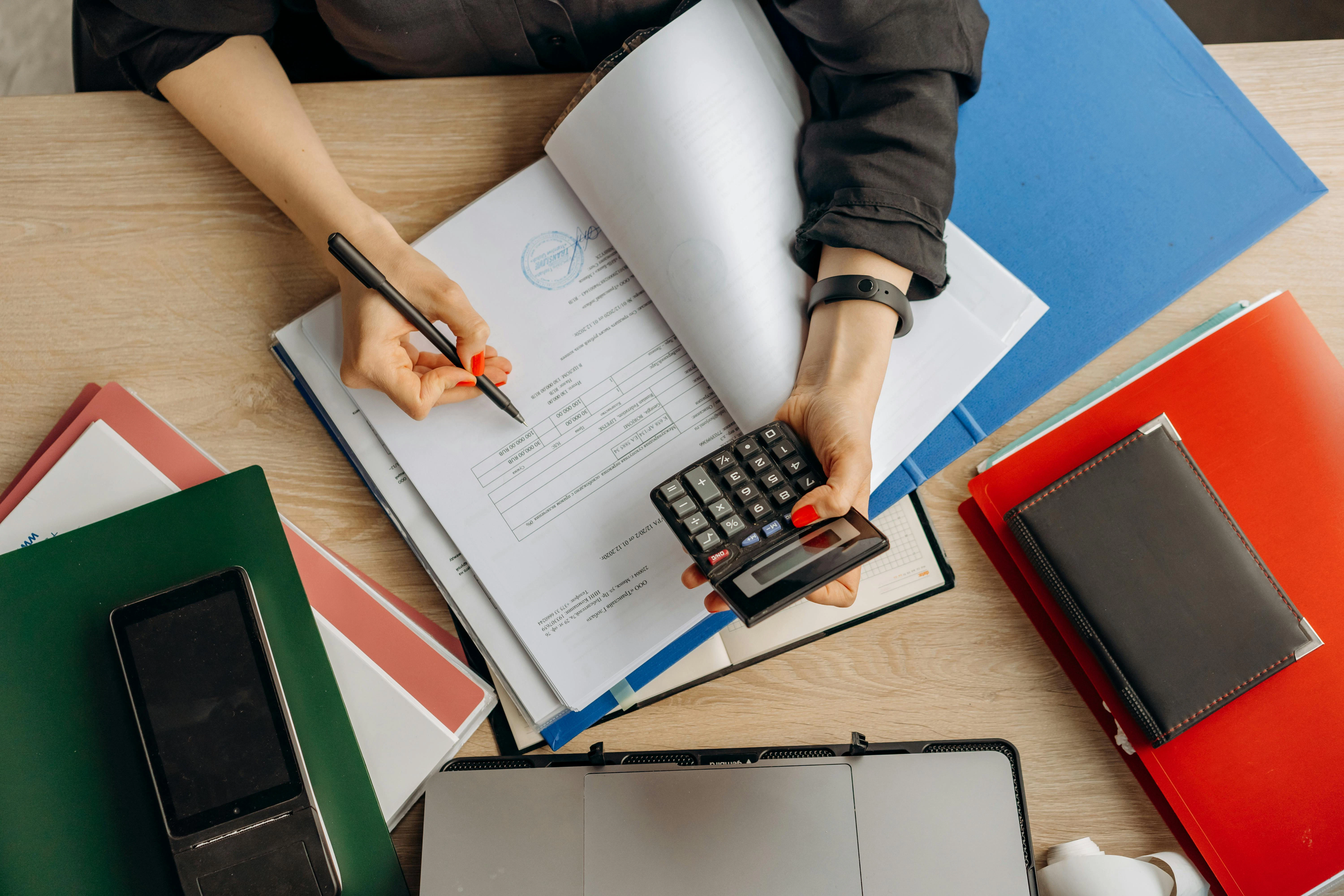 a bookkeeper using a calculator and writing down in financial statements