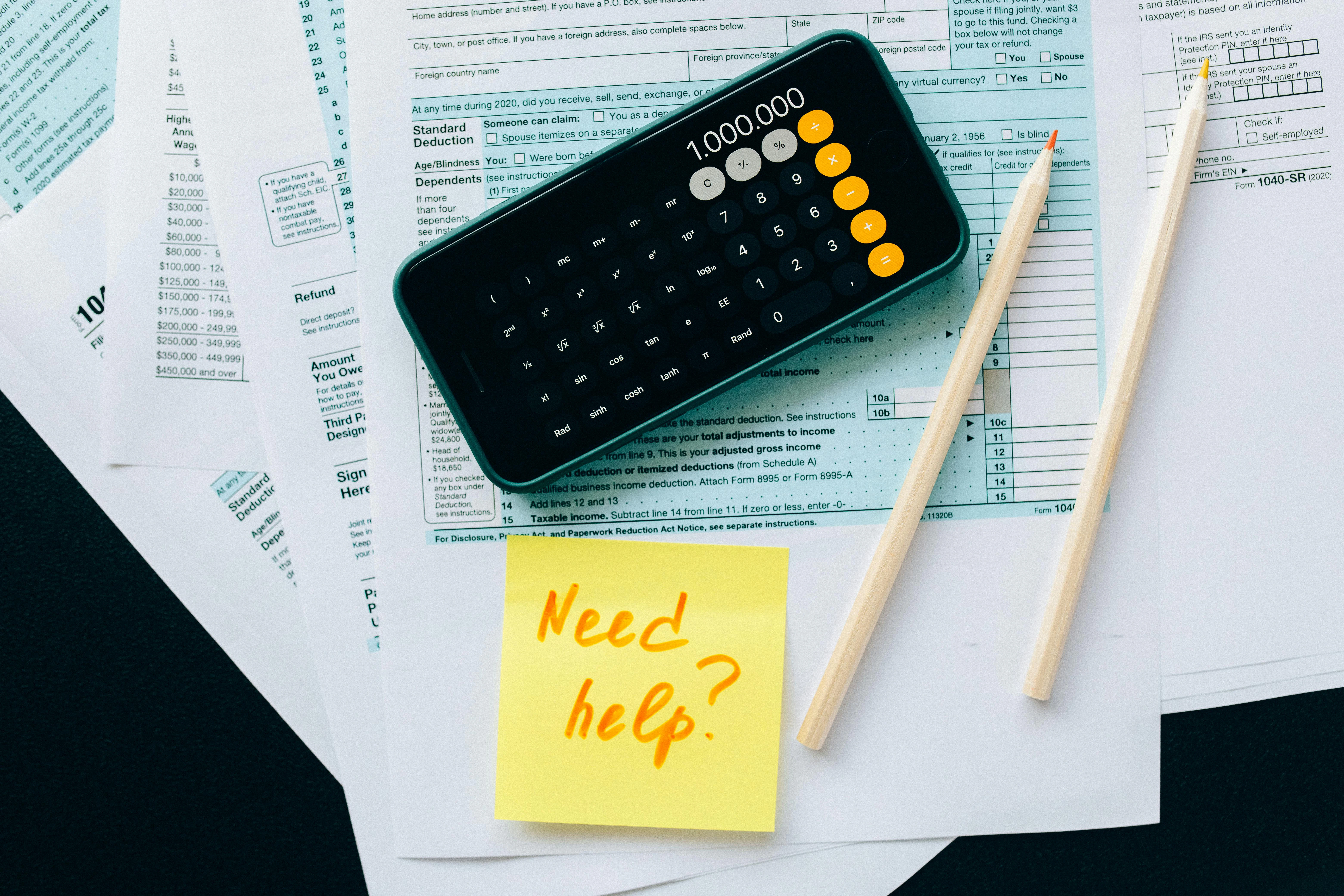 calculator, post-it note, pencils and documents on a table
