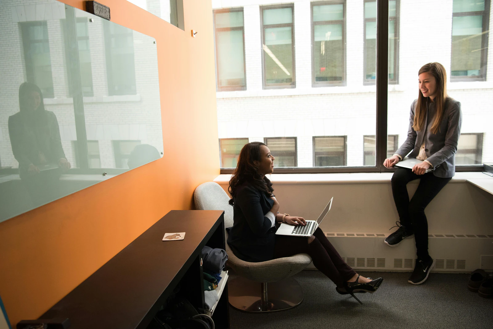 Two women having a one-on-one meeting in a private office nook by a window