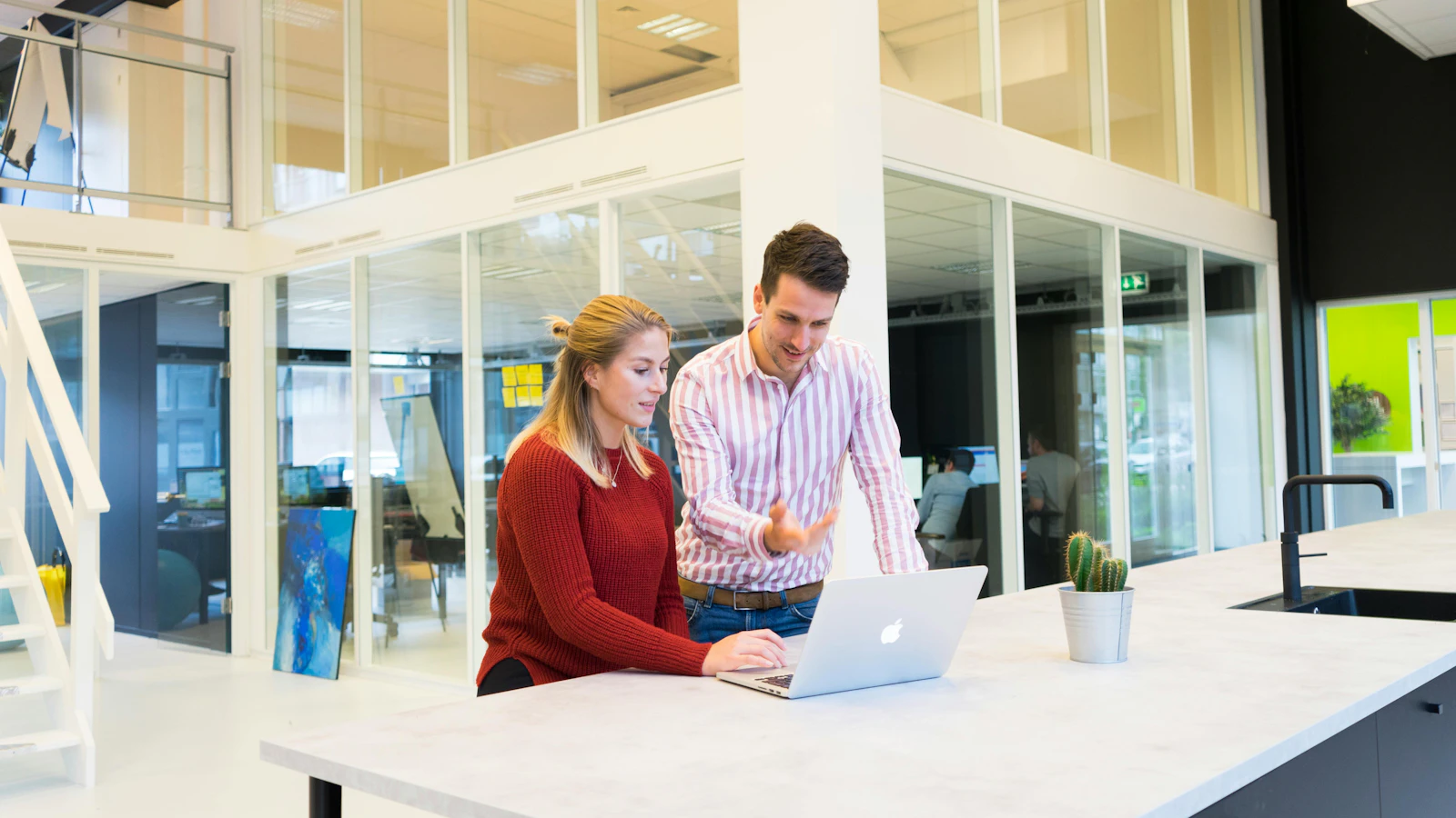 Two colleagues working on a laptop in a modern office