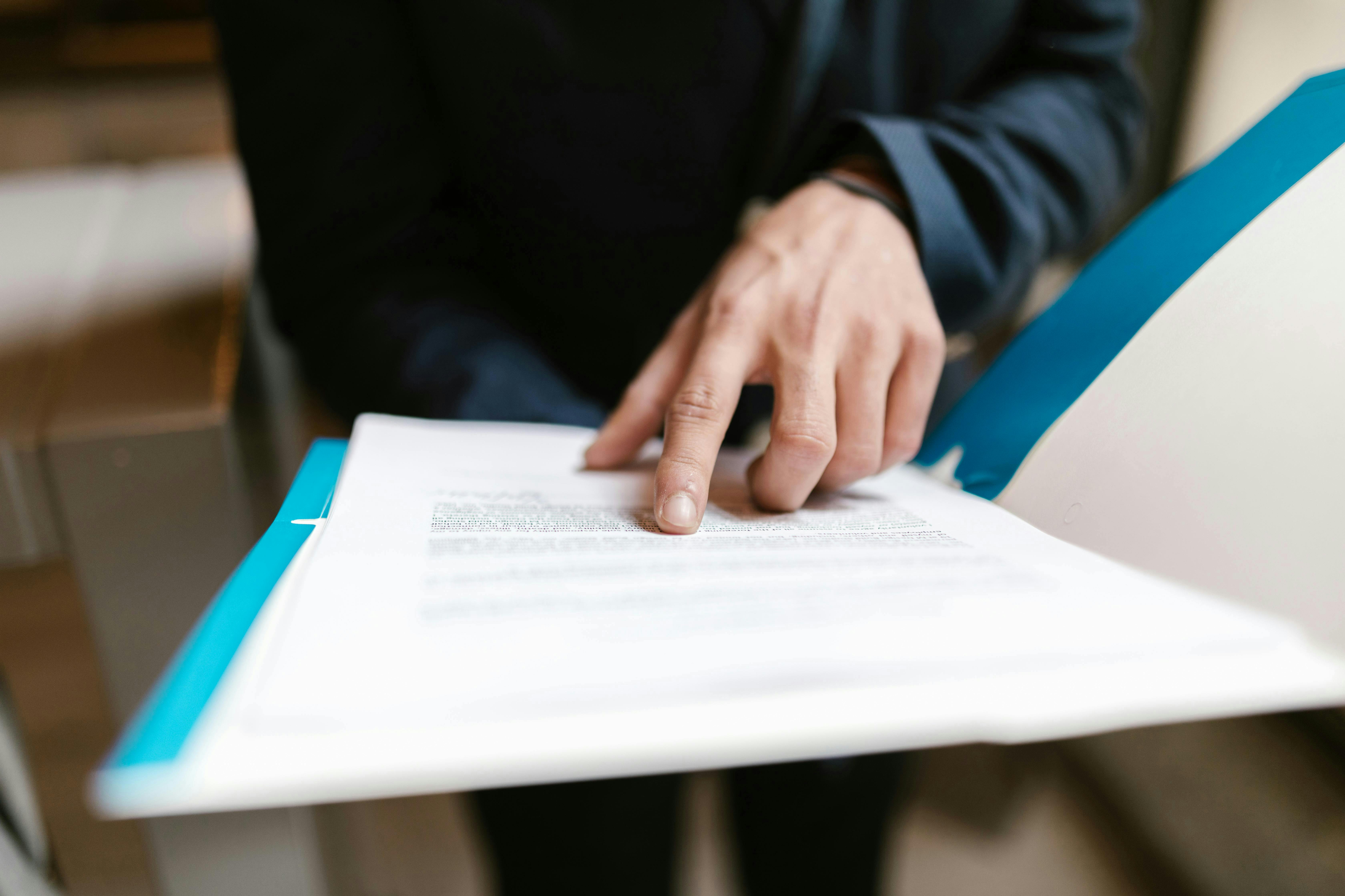 Person Pointing on White Paper