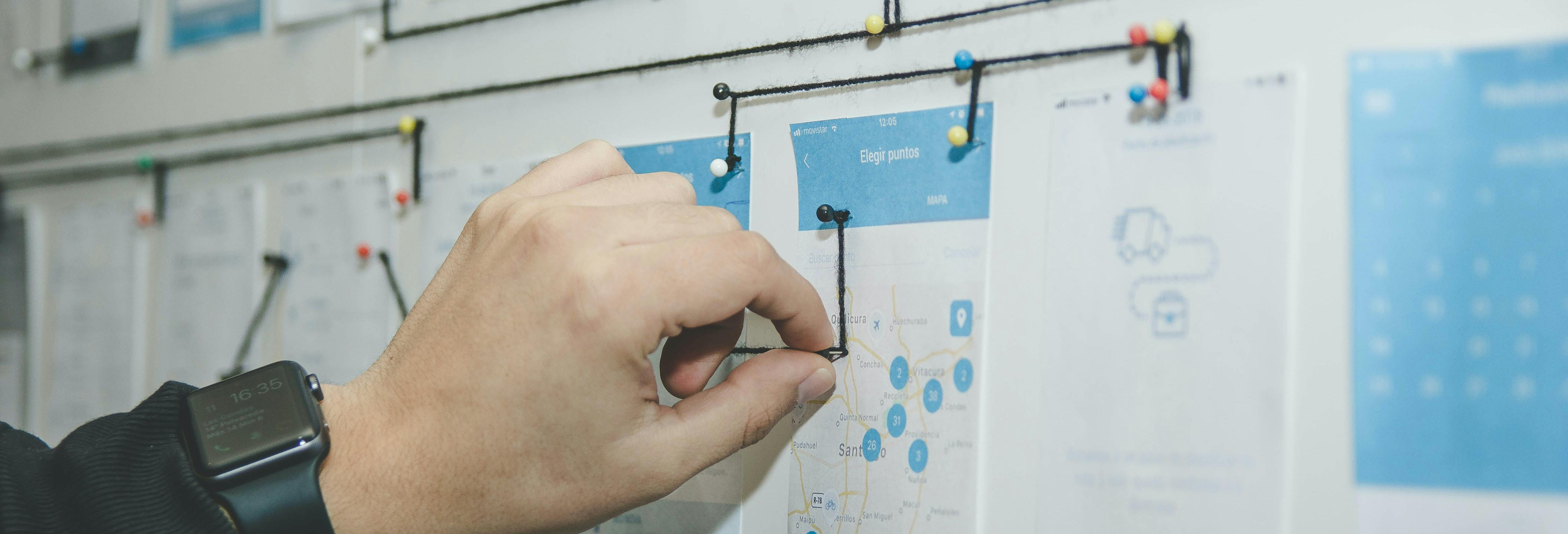 hand working on presentation board with pushpins and string