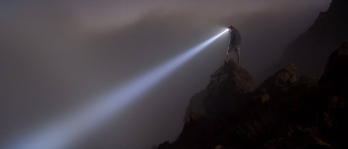 Man with headlamp on mountain covered in mist