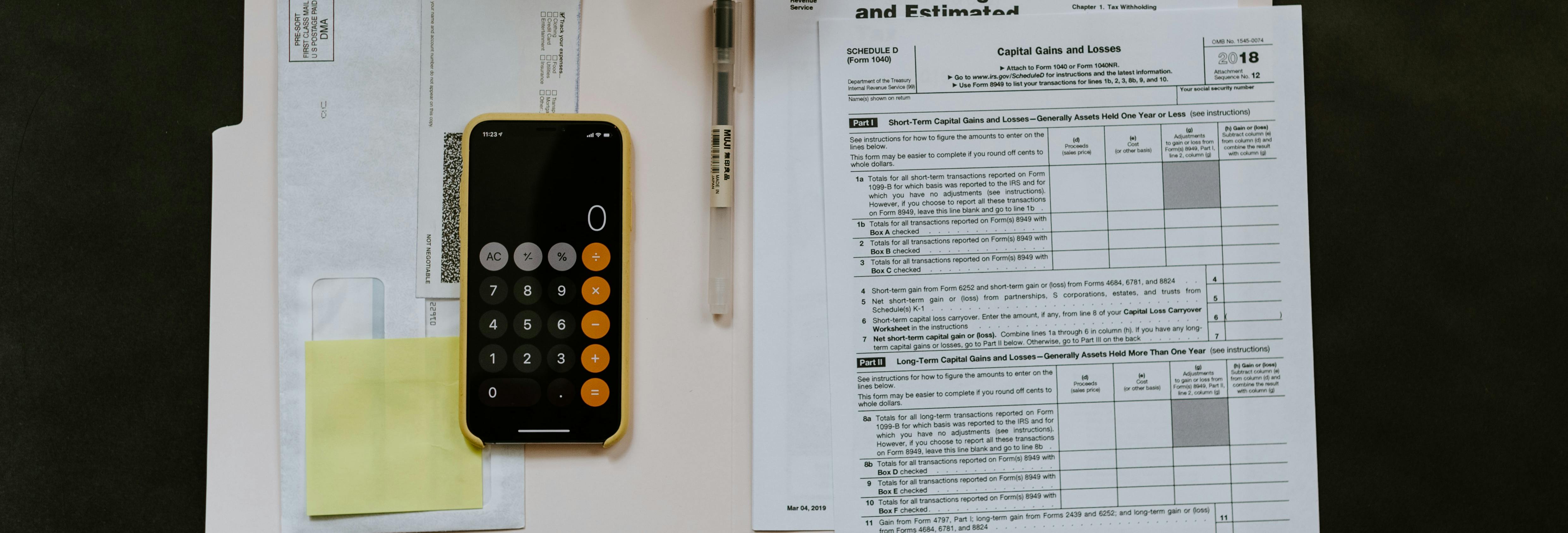 smartphone near ballpoint pen tax withholding certificate on top of white folder