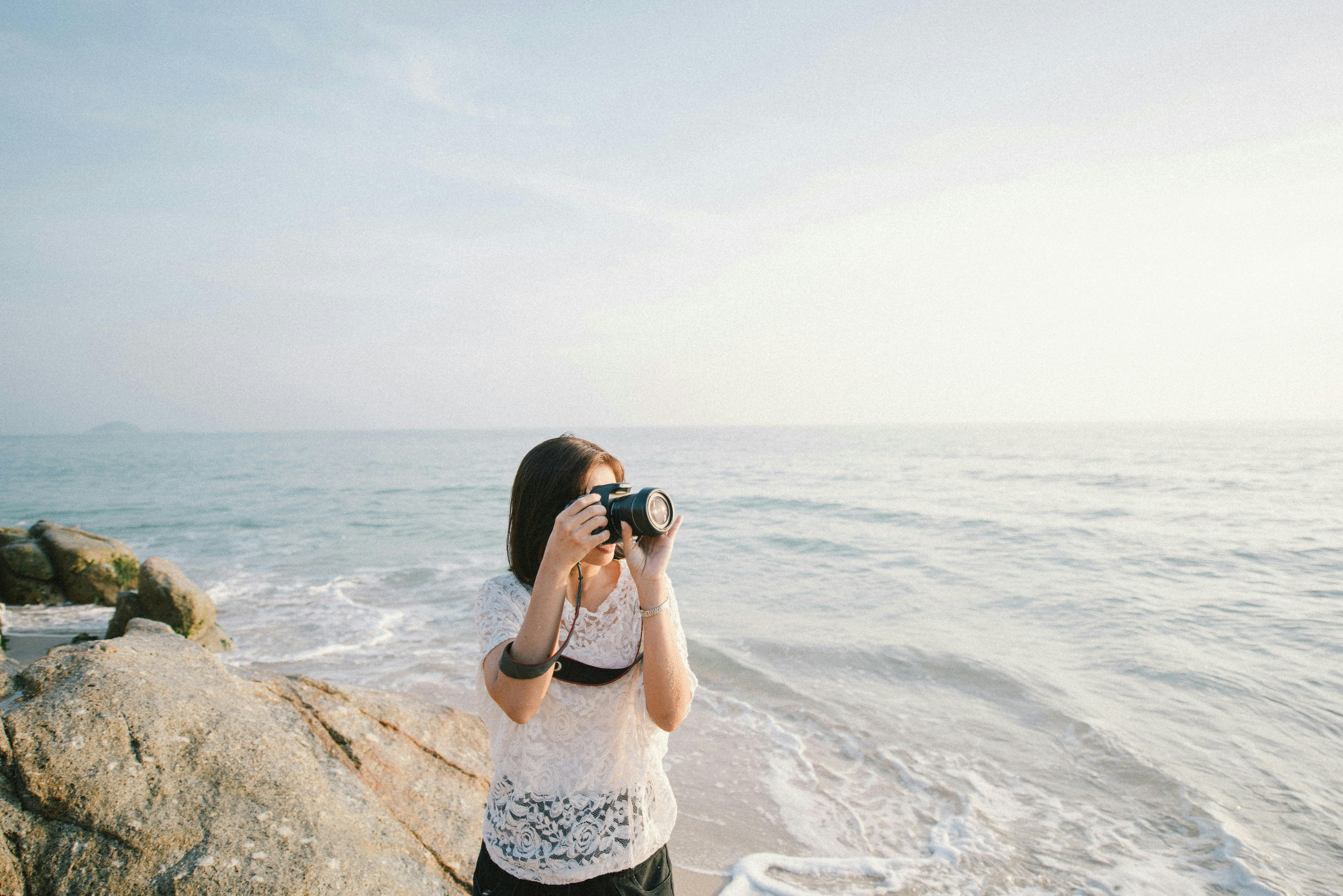Woman holding a camera by the beach