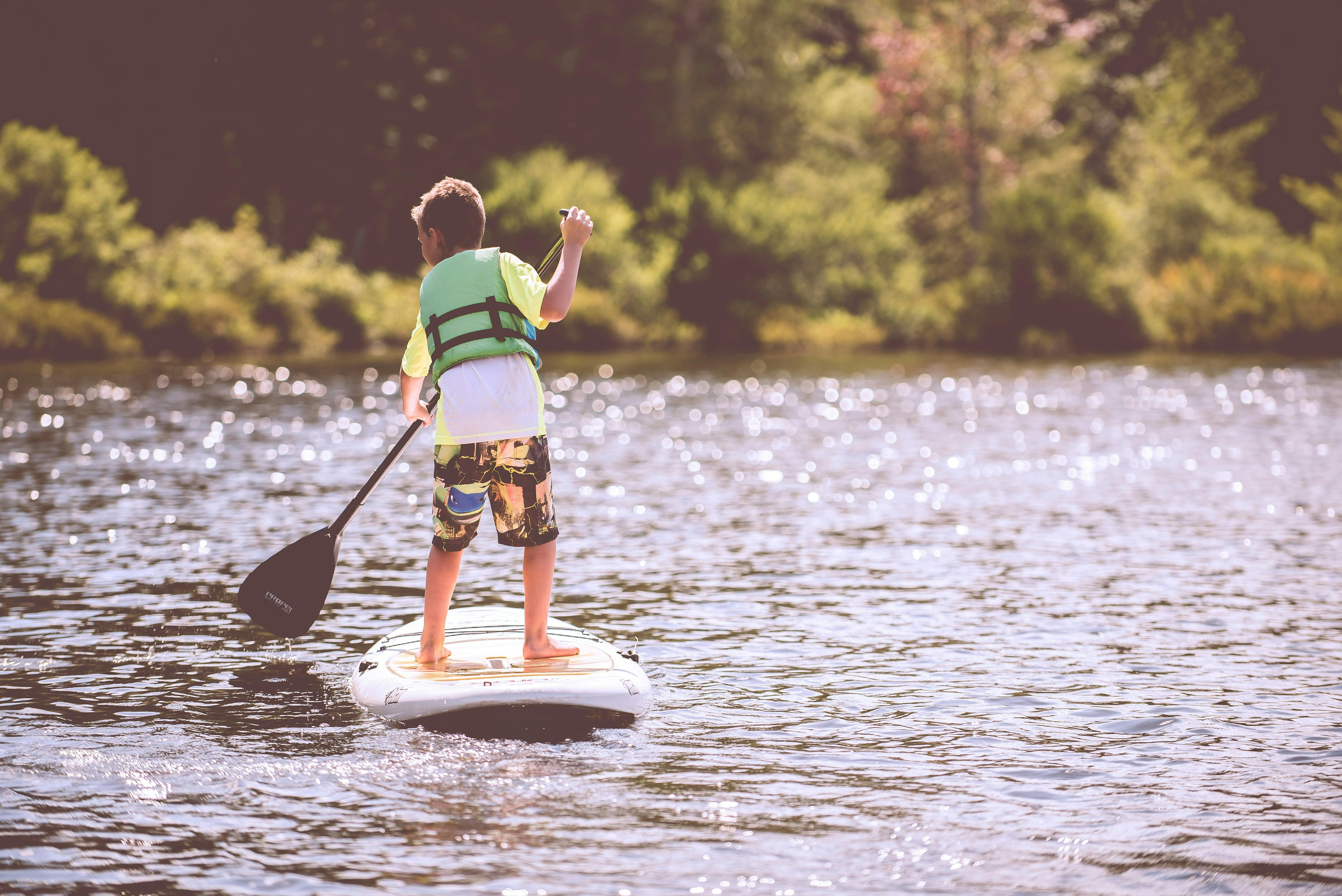 Child standing on a paddle board in a lake