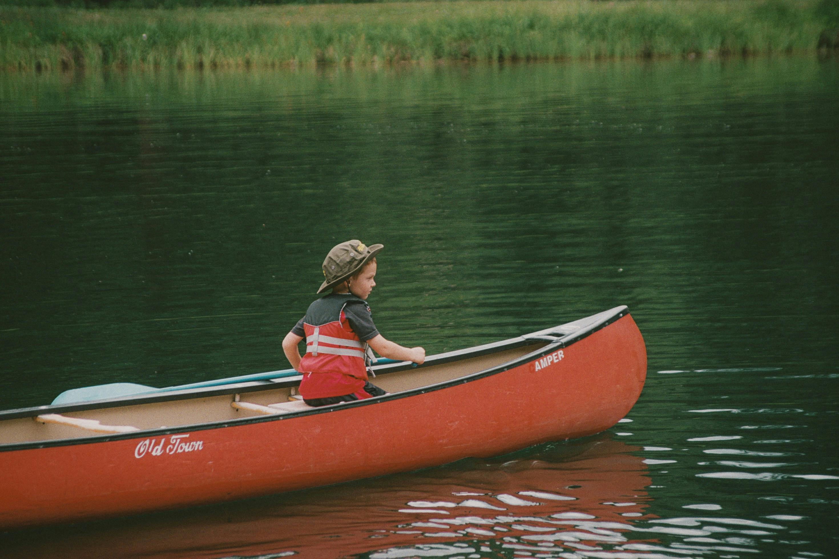 Child wearing life jacket in canoe