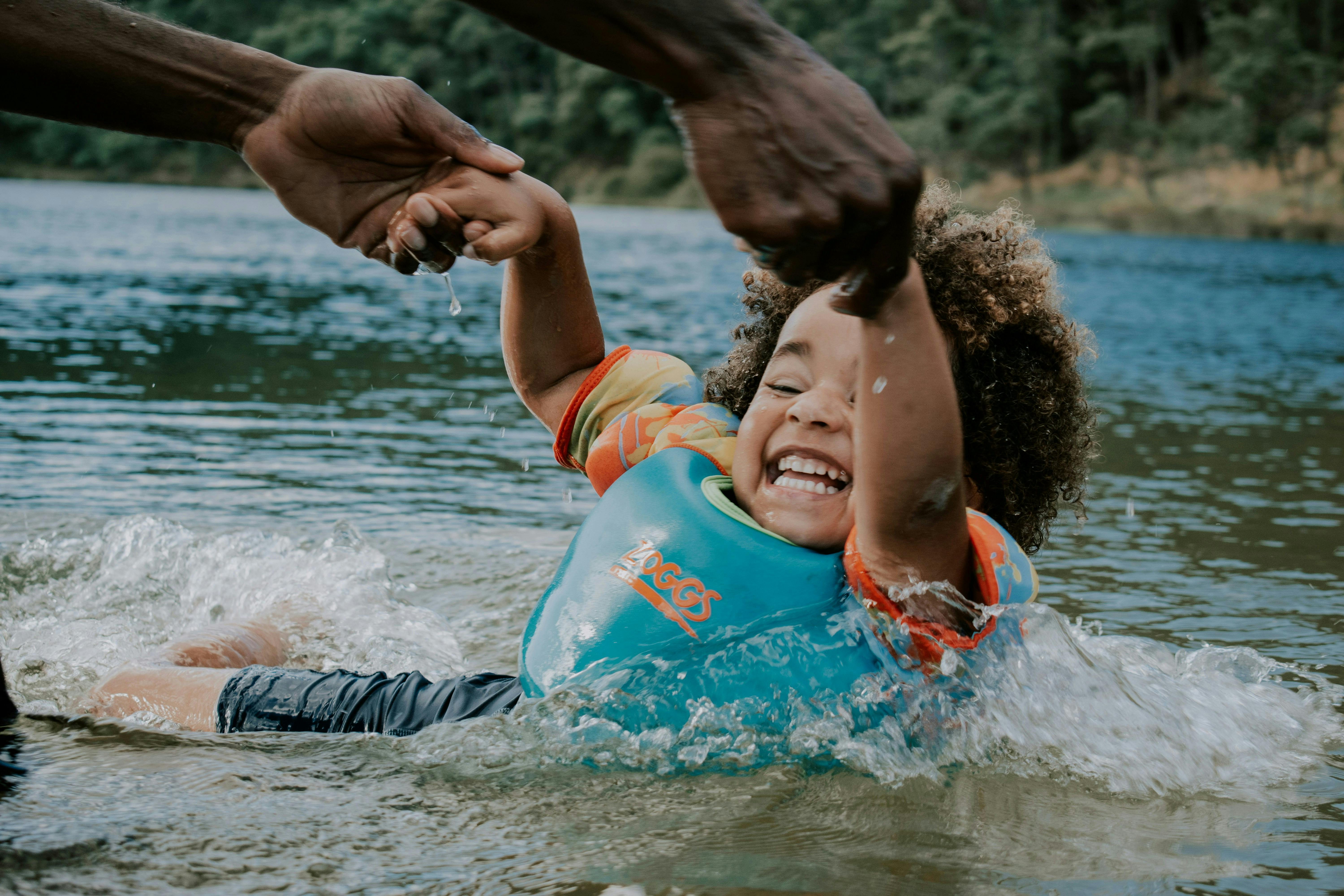 Child wearing life jacket splashing in the water at a lake