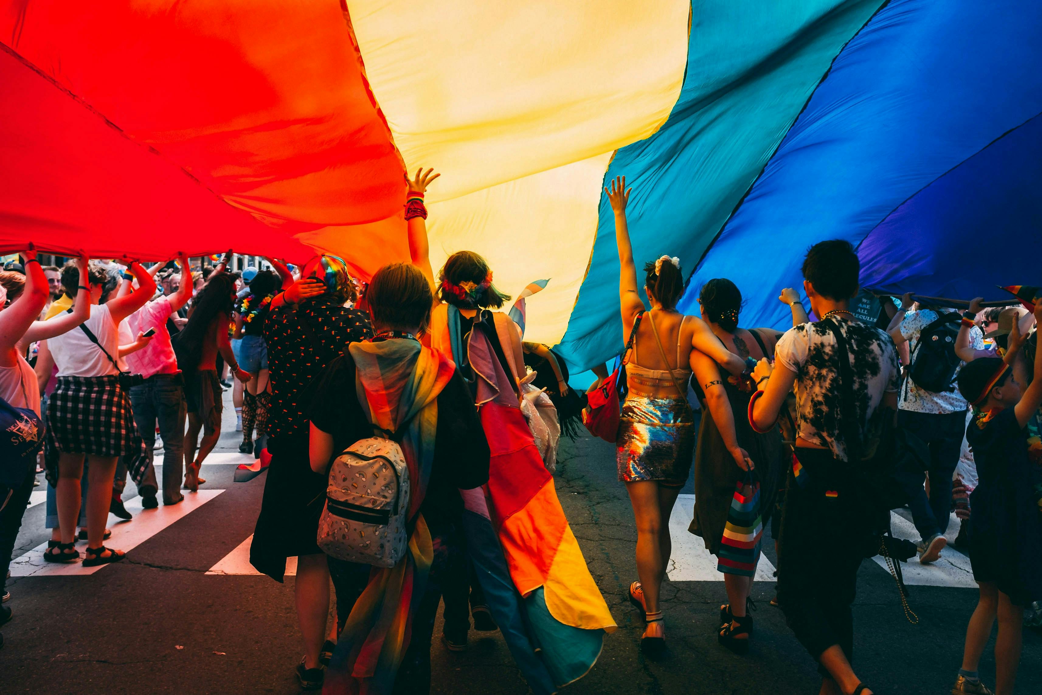 People standing under Pride flag
