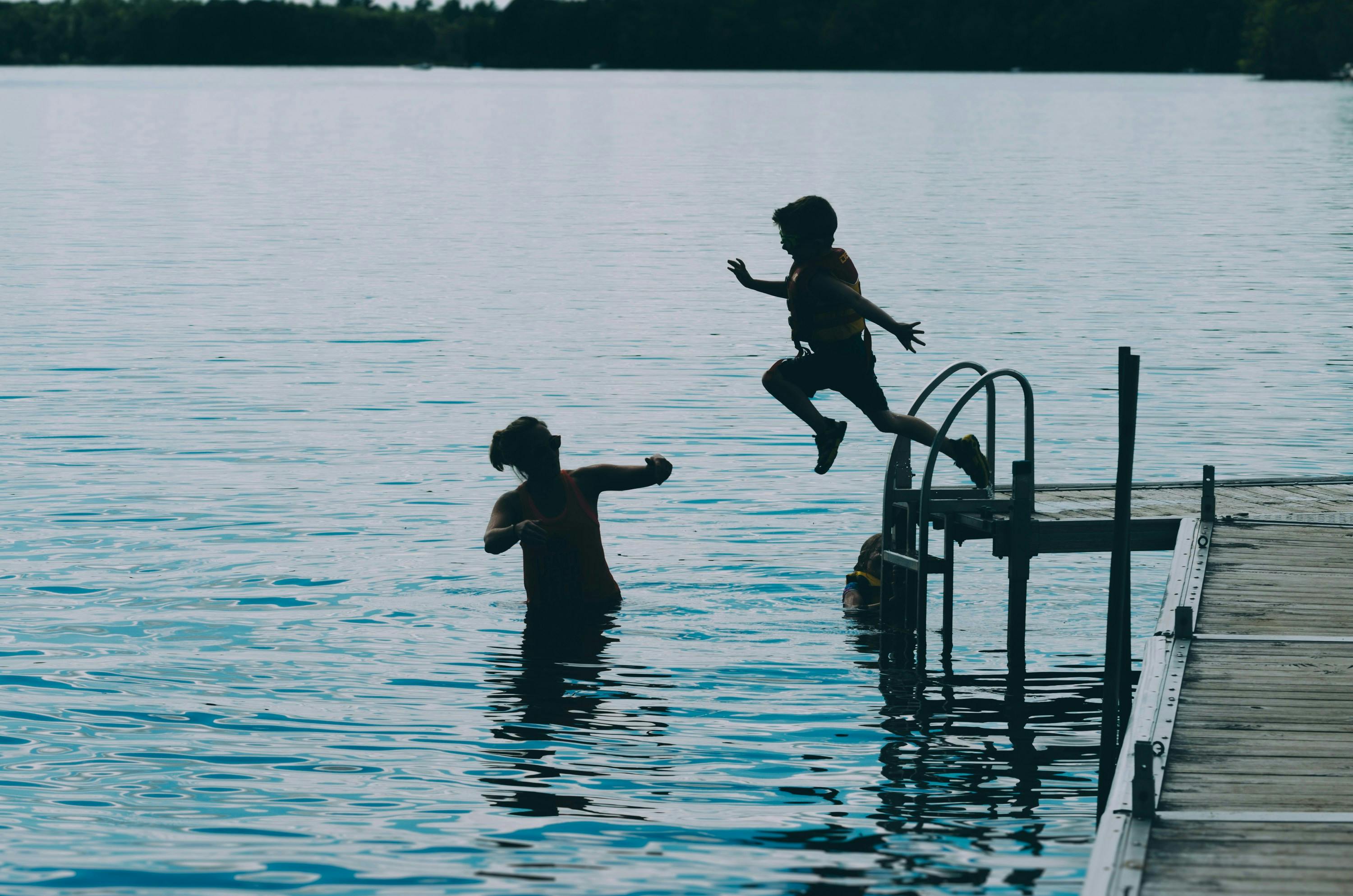 Kid wearing a life jacket jumping off pier