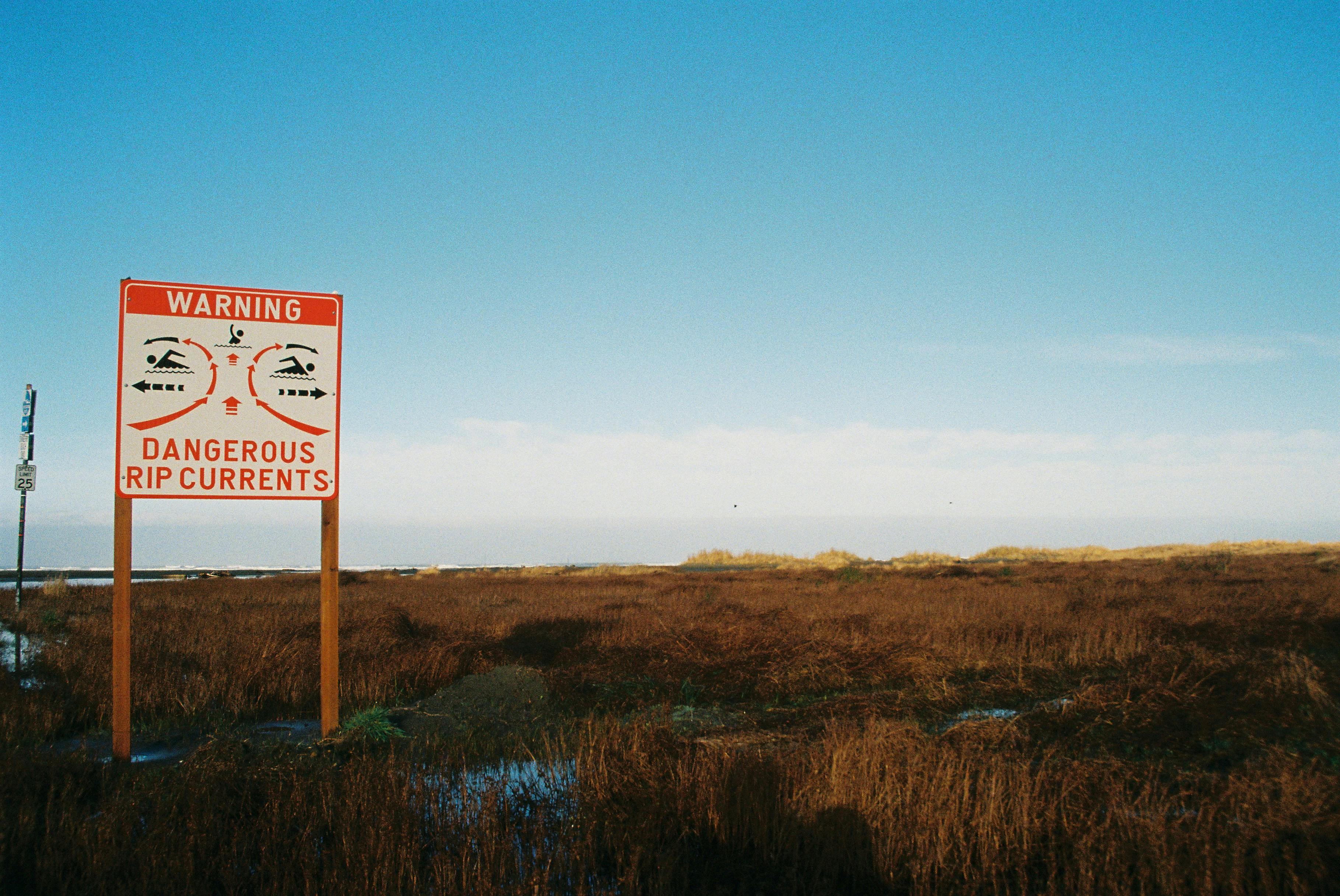  Image of a sign warning of swimmers of rip currents on a beach