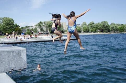 Two girls jumping into the water at Gord Downie Pier in Kingston, Ontario 
