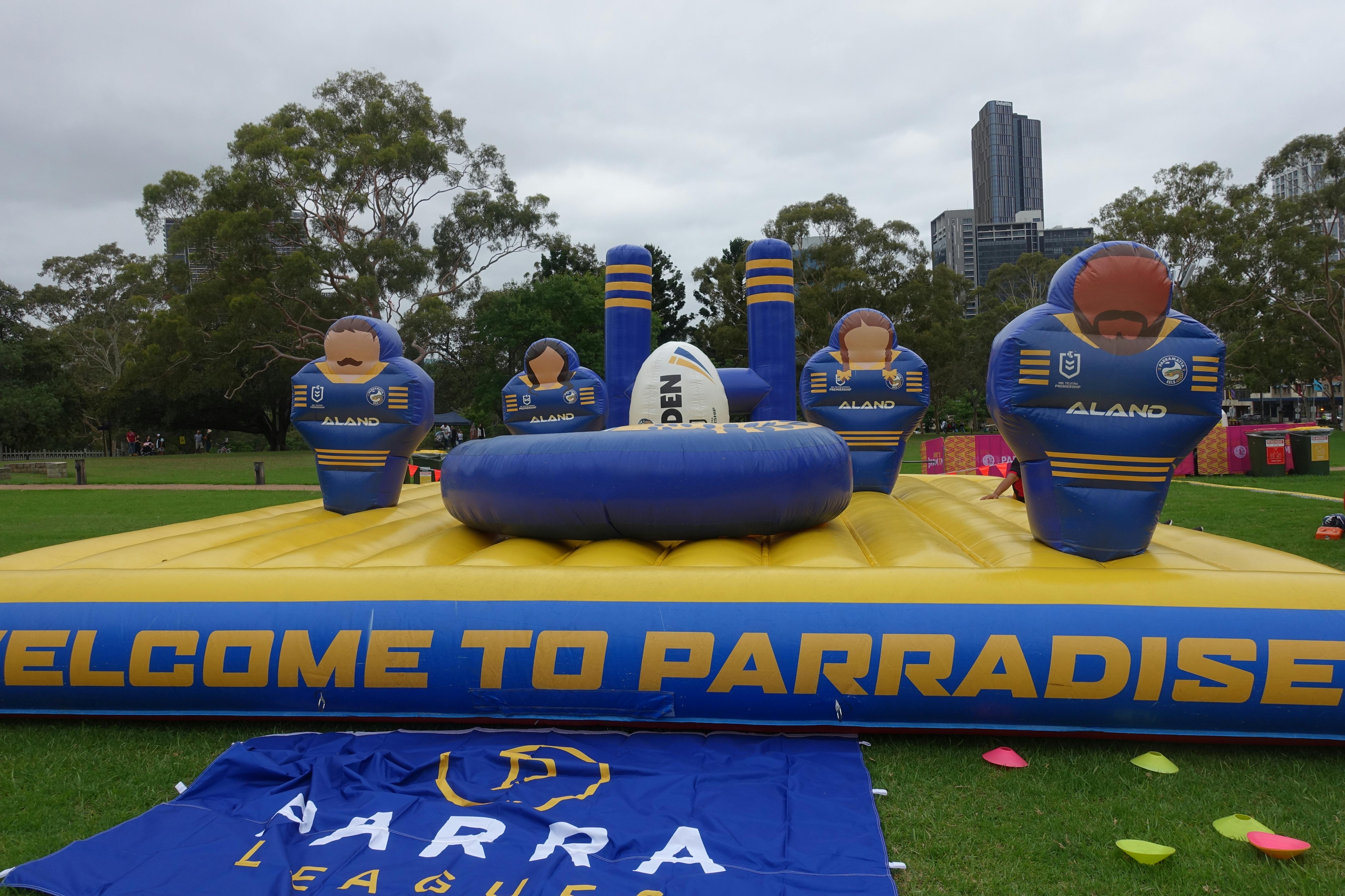 Large blue and gold inflatable banner shaped like a football field, with figures resembling Eels players, a football, and a goal post on top. The banner reads ‘Welcome to Parradise.’