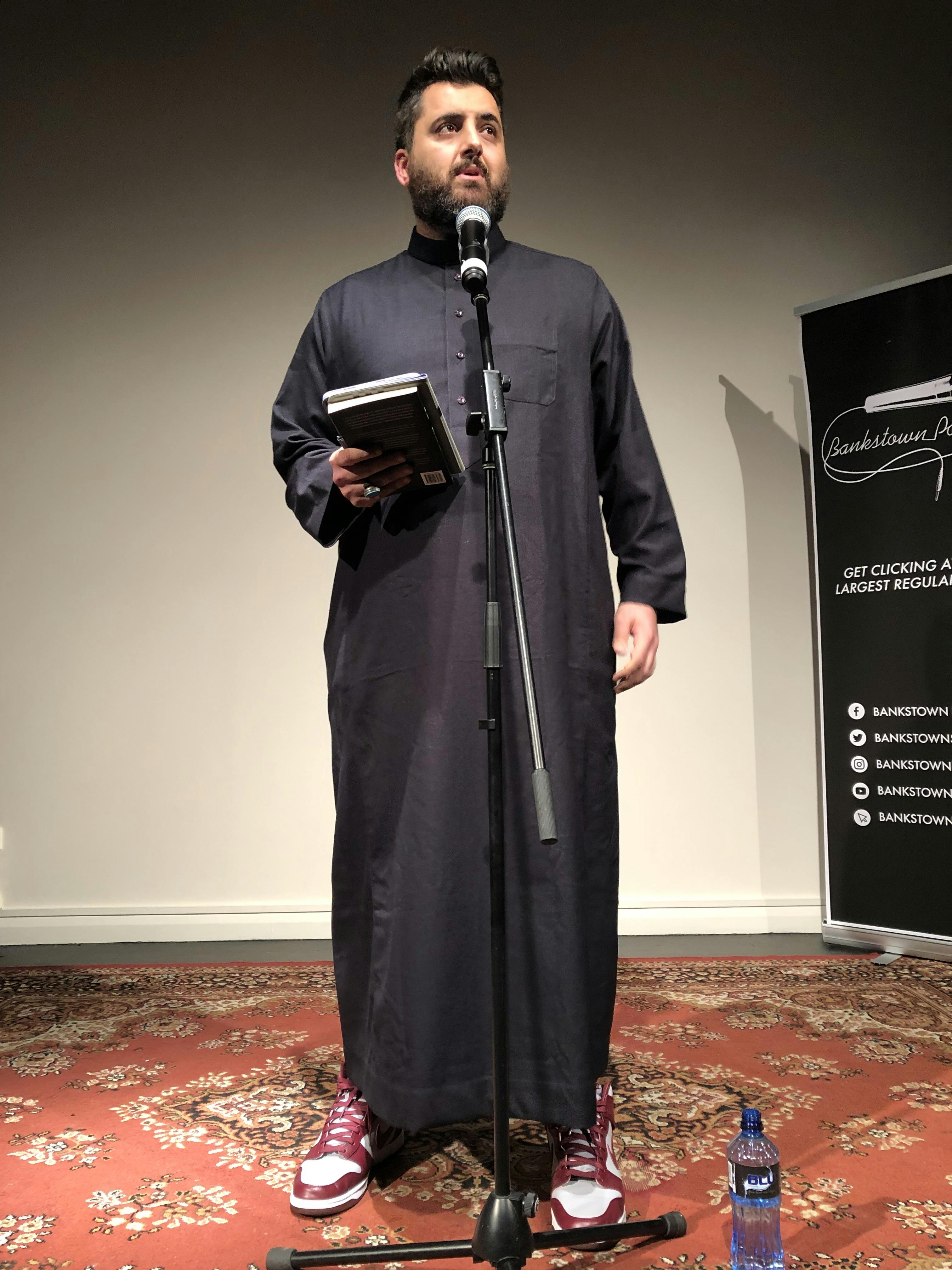 Poet Omar Sakr performing to a crowd at a Bankstown Poetry Slam event.