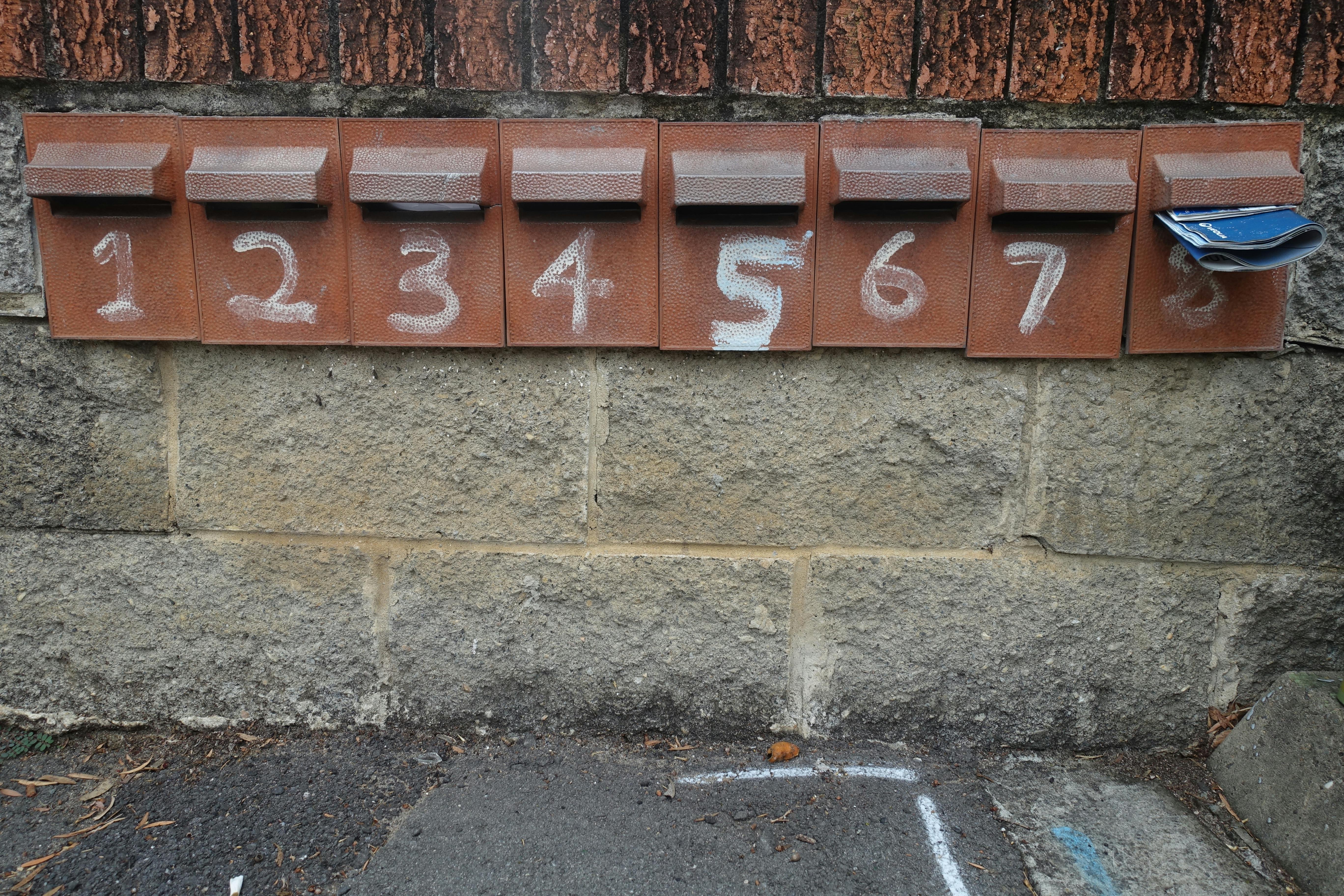 A row of brick mailboxes with the numbers 1 through to 8 painted on. 