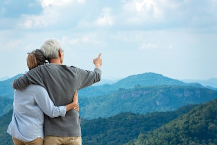 Elderly couple looking at a picturesque mountain viewpoint.
