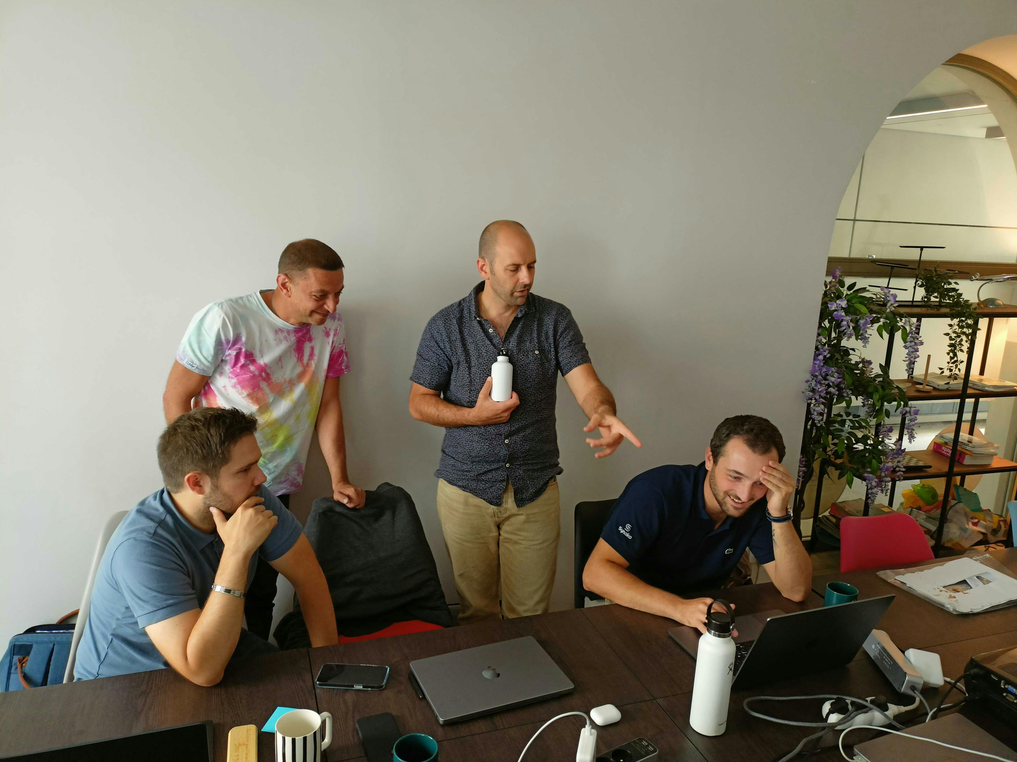 Quatre collaborateurs de Synako échangent ensemble devant la démo d'une nouvelle techno web.