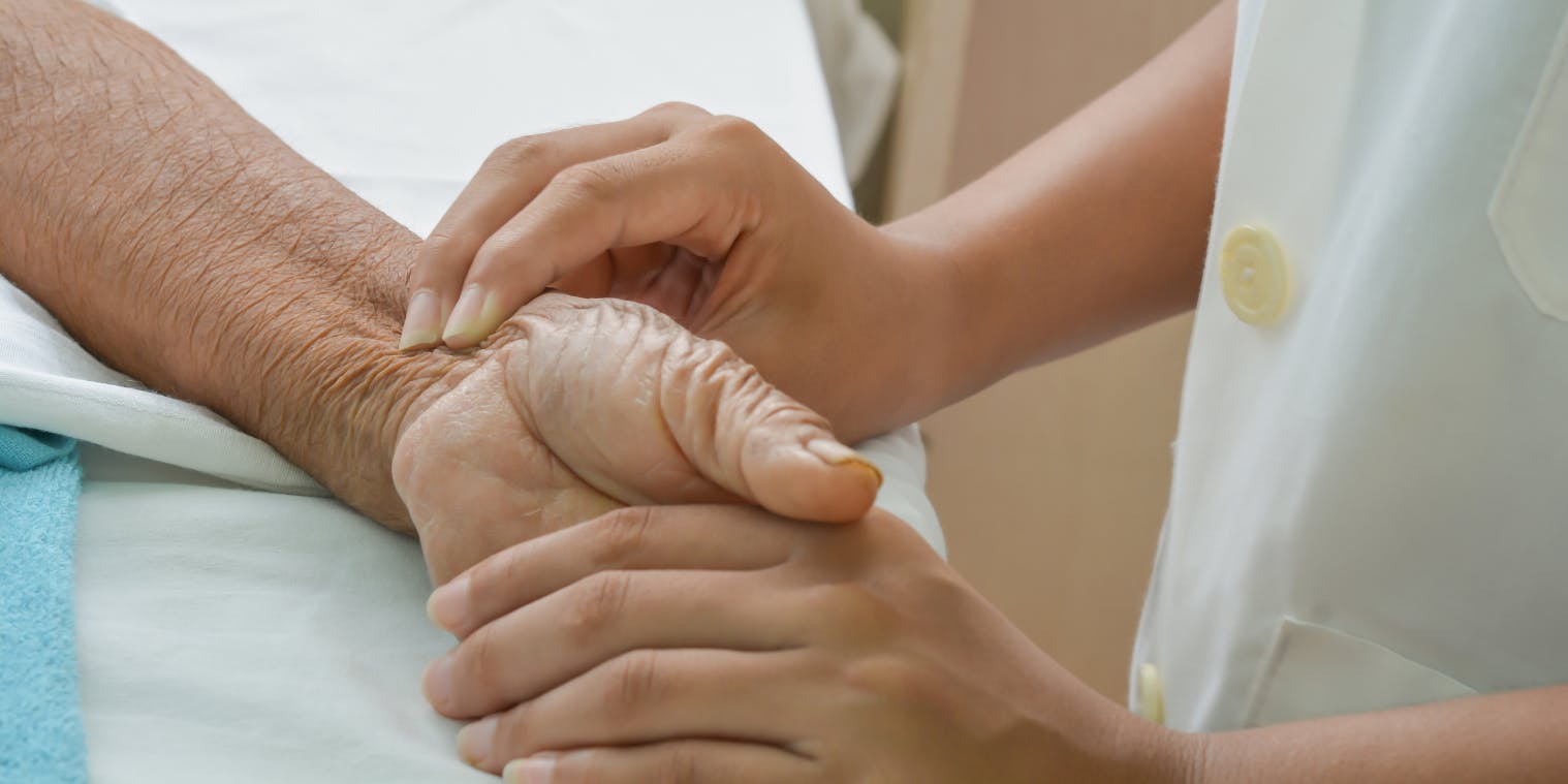 Une infirmière qui tient le bras d'un patient âgé
