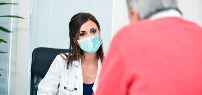 un médecin masqué face à son patient