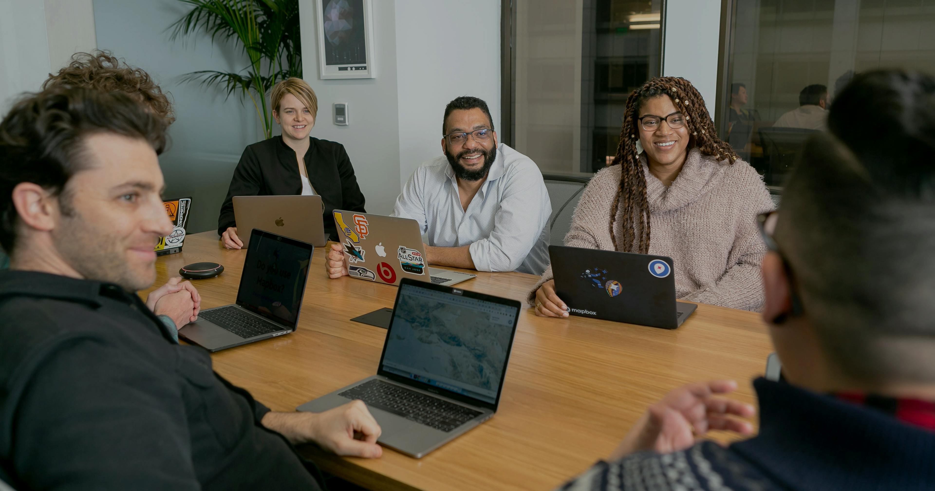 Four people in meeting room on laptops